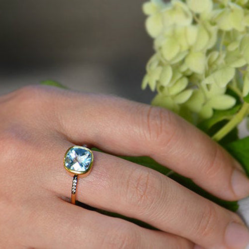 Model is wearing a single Gold plated blue topaz with white topaz pave setting ring. December gemstone, december birthstone, december birthday. Bezel setting. 