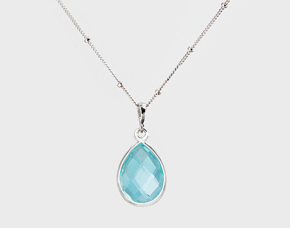 Stamped Sterling Silver satellite chain with blue topaz teardrop pendant gemstone. Tear drop birthstone tear drop gemstone. December birth month, december birthstone on white background. 