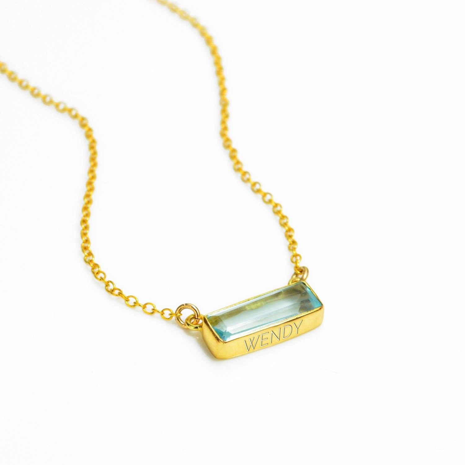 Single gold filled cable chain with horizontal blue topaz december birthstone adira bar necklace with secret message engraved on the bottom in modern thin font on white background