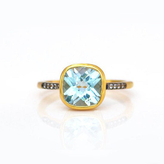 Gold plated blue topaz with white topaz pave setting ring on white background. December gemstone, december birthstone, december birthday. Bezel setting on white background