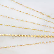 Detailed view of the gold filled rolo, satellite, box, cable, coin and loop anklets.
