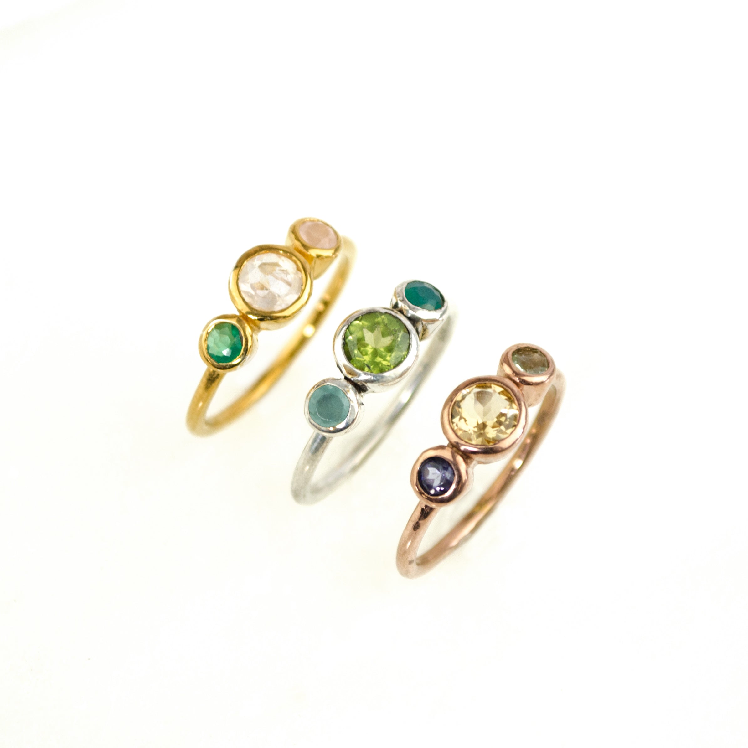 Set of three mothers birthstone rings. First gold filled with 5mm moonstone representing mom and green onyx and pink chalcedony 3mm kids stones. Middle is a sterling silver ring with a 5mm peridot stone and aqua chalcedony and green onyx gemstones. Rose gold filled ring with citrine 5mm mothers birthstone and purple amethyst and blue topaz representing kids birthstones. 