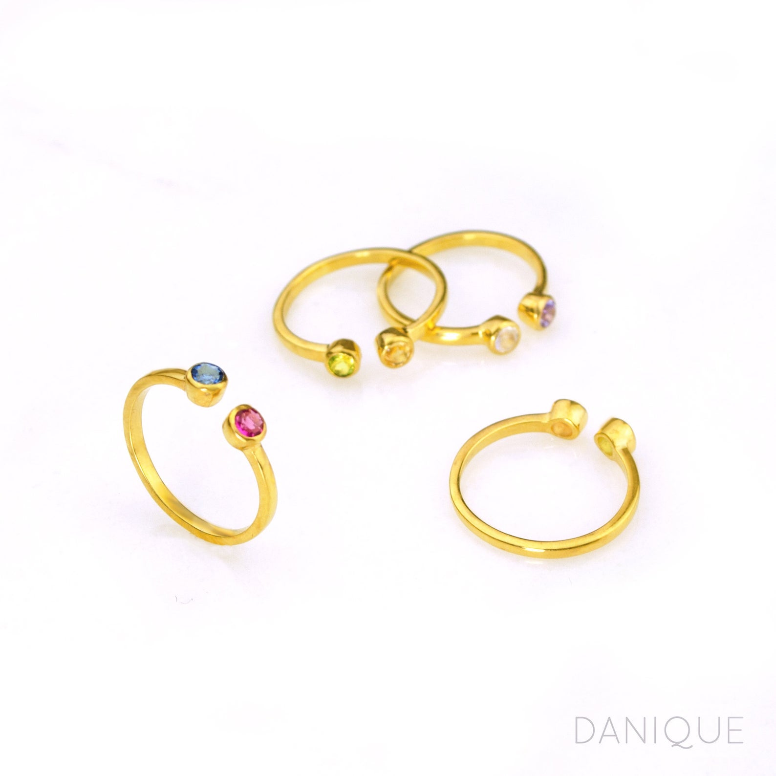 Collection of four custom gold filled dual birthstone rings featuring kyanite, ruby, peridot, citrine, clear, and purple amethyst. Back of citrine and peridot ring shown