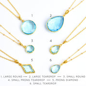 Shop our blue topaz necklace collection available in large, medium and small teardrops, prong set teardrop, prong set diamond, large and medium rounds on white background. Choose from satellite or cable chain. December birthstone. 