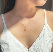 Model in white top is wearing a gold filled satellite chain flower bloom necklace with peridot birthstone. 