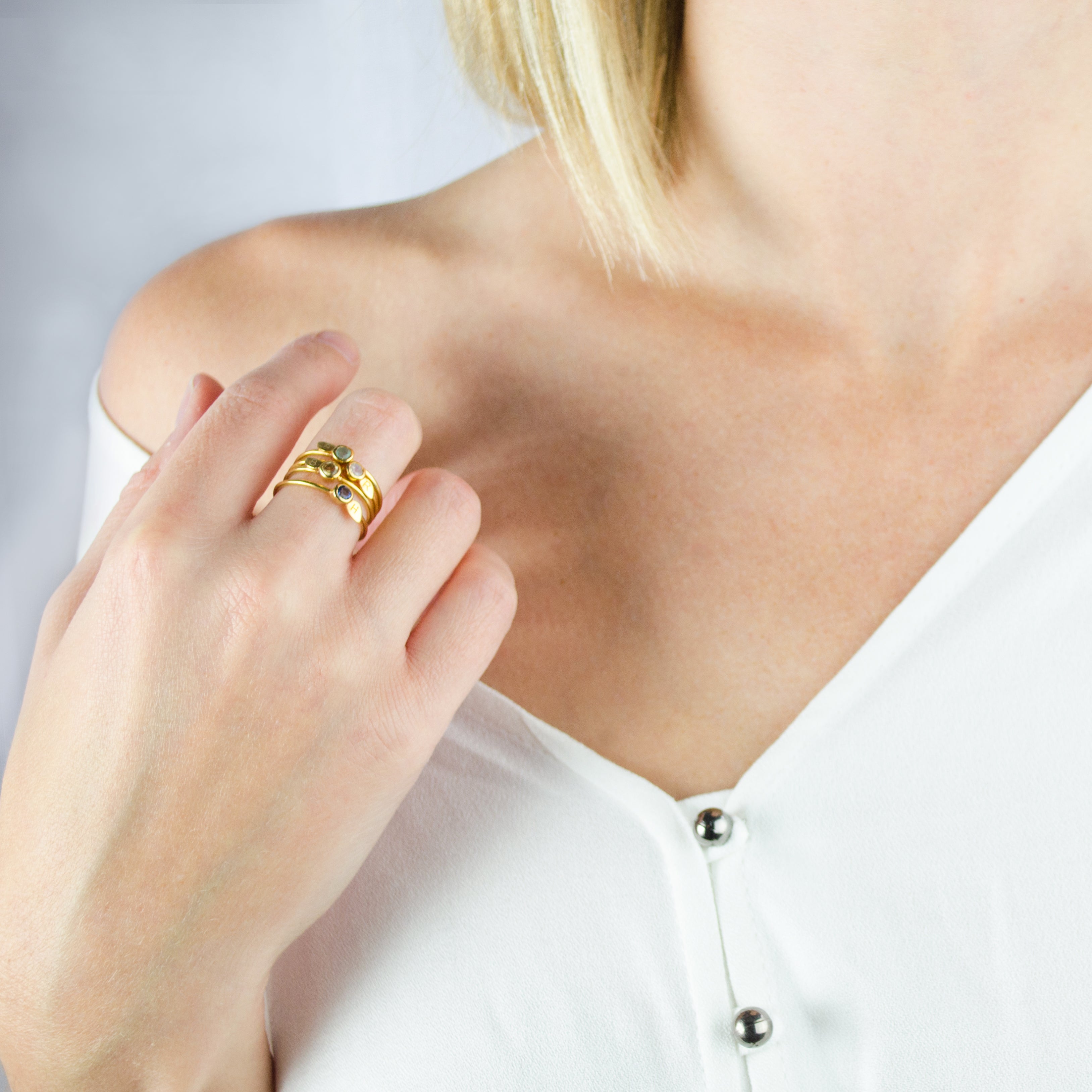 Model wearing a collection of stacking leaf birthstone rings with engraved initial on the front of ring leaf. 
