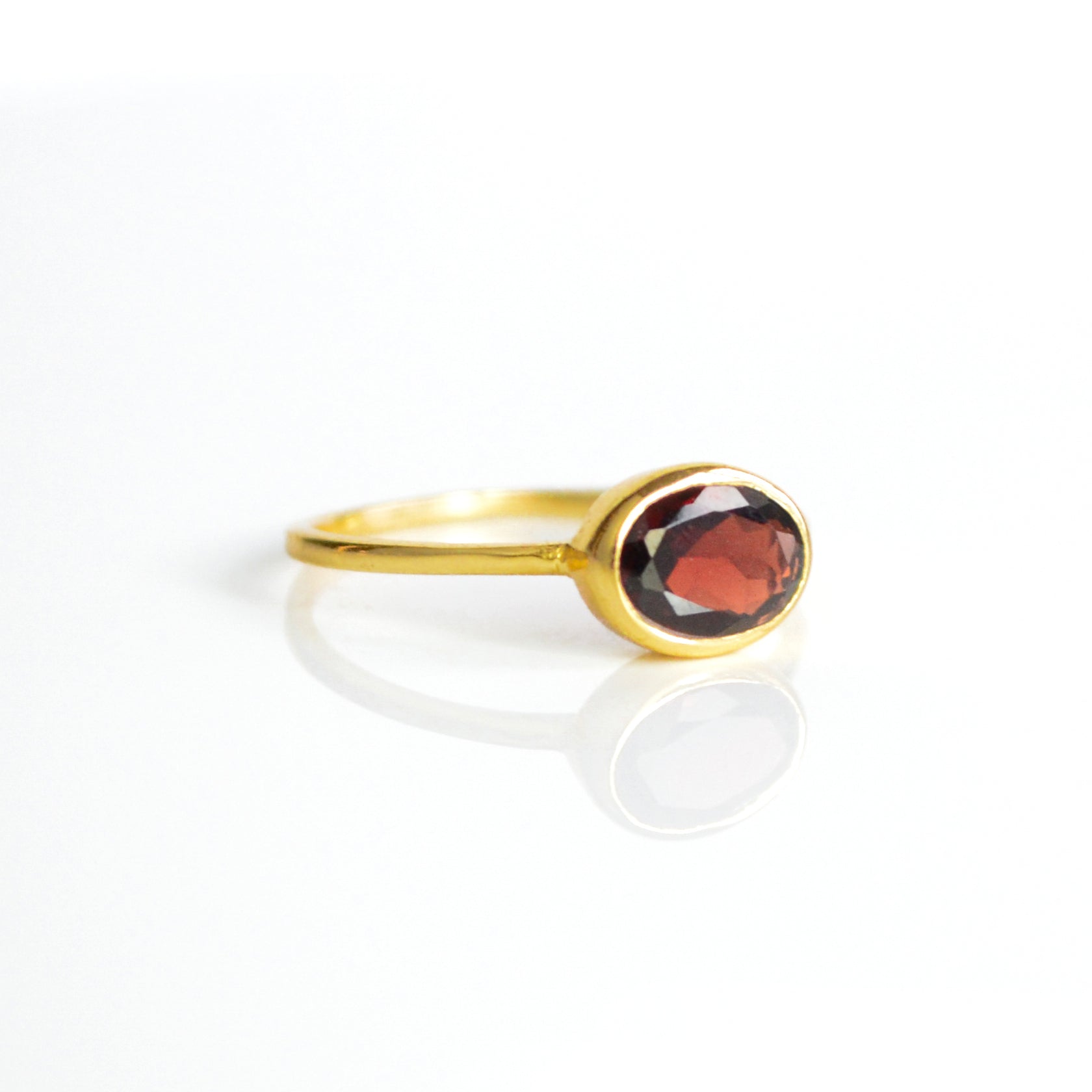 a gold garnet ring shown on white background. stackable! Stacking rings, bezel set, birthstone jewelry, red gemstone, red birthstone, january birthstone, january gemstone, stack set, stacking rings, gemstone ring, birthstone ring, mother's day gift for her, gift for mom, gift for fiance, gift for girlfriend, wedding jewelry, bridesmaid jewelry, anniversary jewelry, anniversary gift, birthday gift, christmas gift, valentine's day gift, valentine's day rings, dainty ring, cocktail ring, statement ring