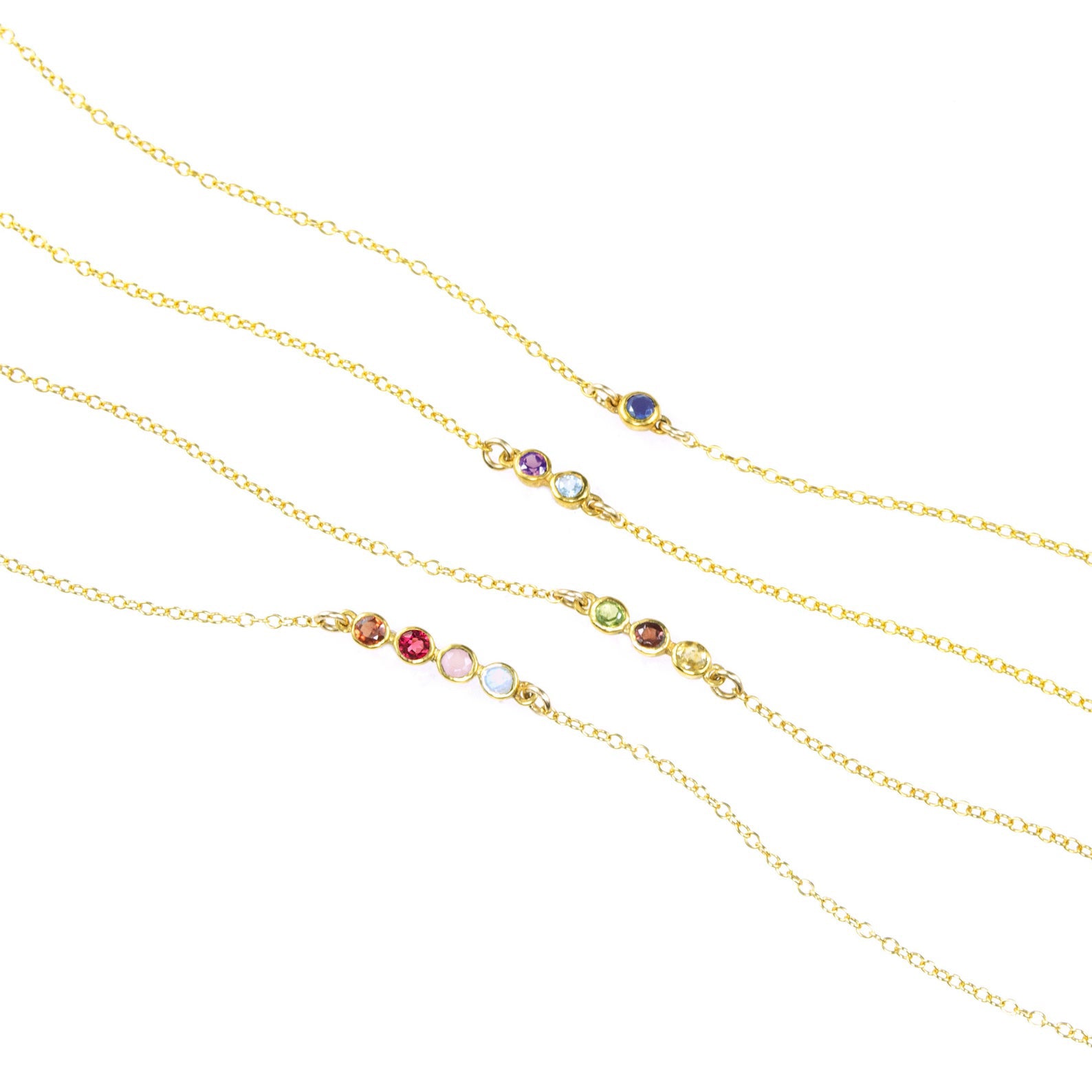 This necklace can hold 1, 2, 3, or 4 birthstones on this bar setting. Necklace with single Iolite birthstone. Middle necklace with two birthstones including purple amethyst and blue topaz. Middle necklace featuring 3 stones are peridot, garnet and citrine. Last necklace has four birthstones including garnet, ruby, pink chalcedony and blue topaz