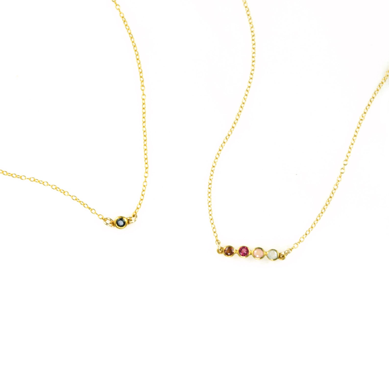 Two dainty birthstone bar necklaces show. One gold with single kyanite stone. Second necklace has 4 birthstones including ruby, garnet, pink chalcedony and green amethyst.