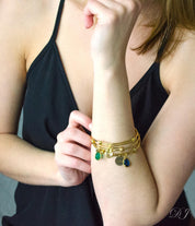 Model in black top is stylishly layering three gold bangles with citrine, green onyx and kyanite birthstones