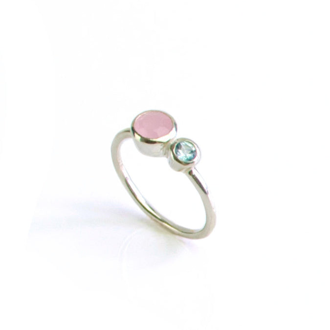 Single mothers duel bezel set ring in sterling silver featuring a 5mm pink chalcedony and 3mm blue topaz birthstones on white background