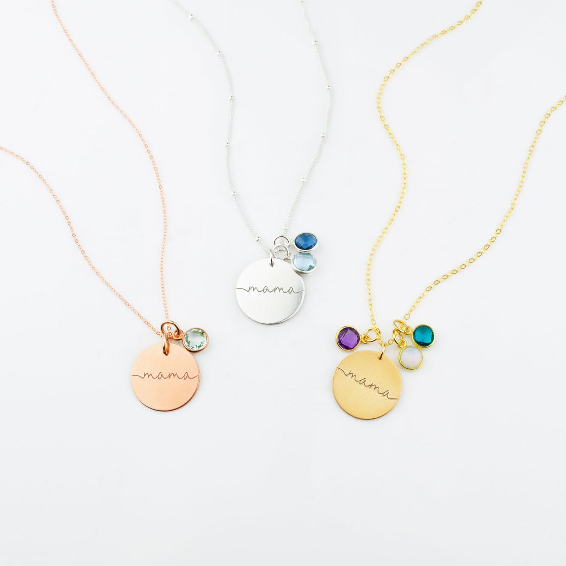 Mama 19mm disc necklaces come in rose gold filled, sterling silver or gold filled. Necklaces from left to right are a single rose gold filled mama necklace and green amethyst stone, single silver mama disc necklace with satellite chain and sky blue and kyanite stones. Third, gold filled mama disc necklace with purple amethyst, moonstone and kyanite birthstones. 