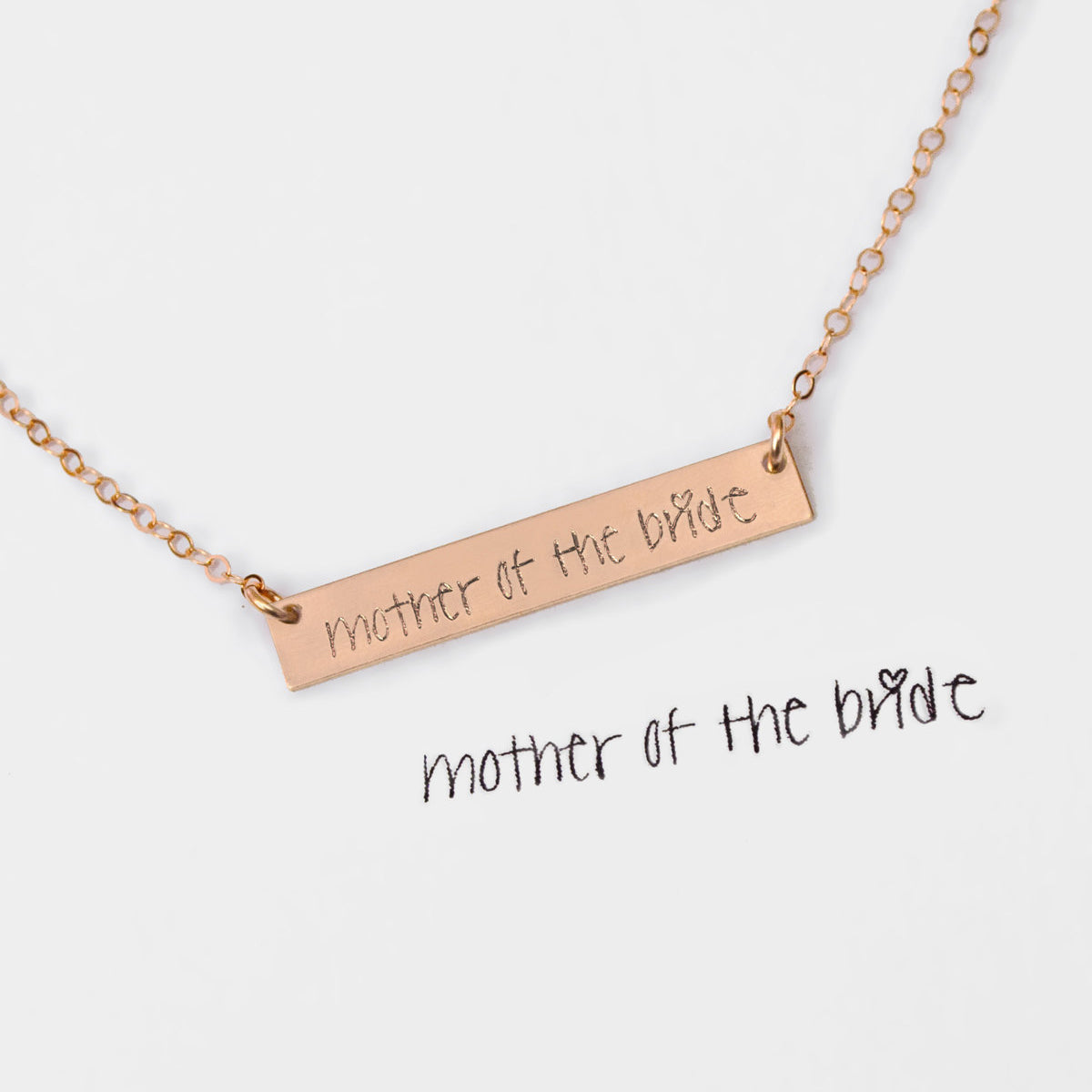 A rose gold bar necklace engraved with mother of the bride in actual handwriting against a white background. Mother of the bride jewelry, custom engraved bar necklace, personalized minimalist bar necklace, actual handwriting engraved jewelry, gift for future MIL, gift for future DIL mother-in-aw or daughter-in-law