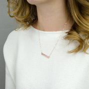 A person in a white sweater wears a rose gold bar necklace. Personalized bar necklace with special date Custom bar pendant for men with engraving Engraved minimalist necklace for special moments Personalized bar necklace for significant other Custom engraved bar pendant for best friends Minimalist bar necklace for personalized gifts Engraved bar pendant for holidays Custom bar necklace for memorable occasions Personalized minimalist jewelry piece