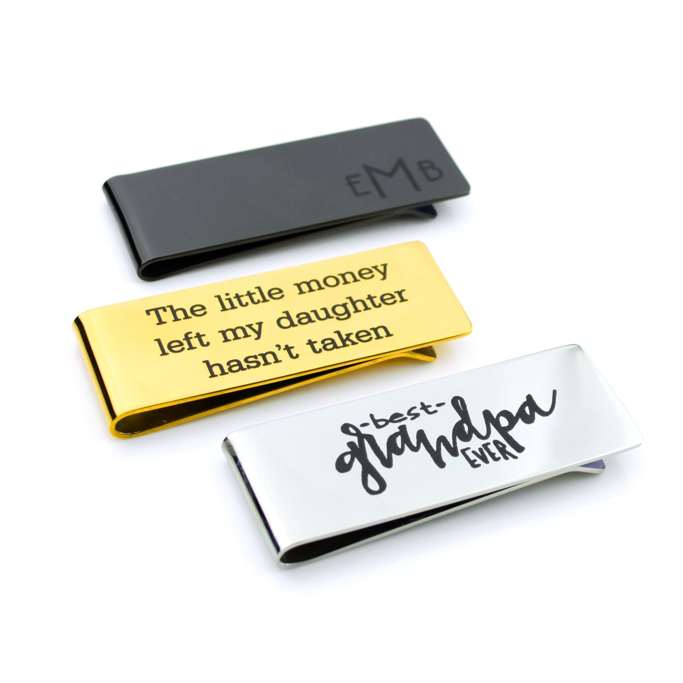 Personalized money clip in stainless steel shown in three finishes—black, gold, and silver—with custom engraving examples including a classic monogram and a witty phrase. Sleek, minimalist cash holder designed for men who prefer a slim wallet alternative. Ideal as a personalized gift for Dad, groomsmen, or graduates; features durable laser engraving that won’t fade, and optional front and back customization for names, dates, coordinates, or handwriting.