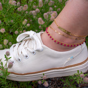 Model wearing four anklets from our collection all gold filled including the ruby wire wrap anklet, pet paw print bar, cable and box chain anklets. Perfect for layering!