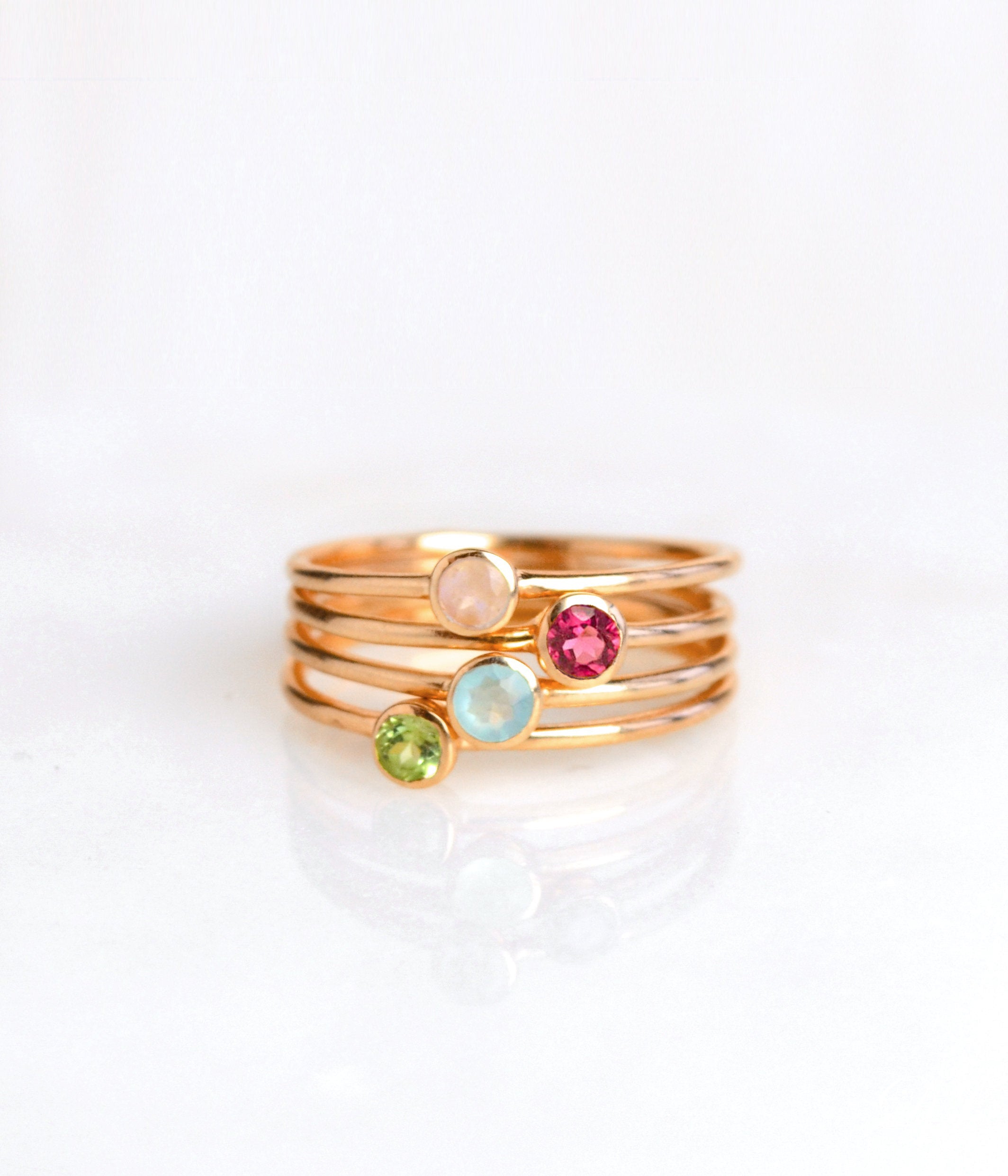 set of four rose gold plated dainty 3mm gemstone rings featuring pink chalcedony, ruby, aqua chalcedony and peridot. July  birthstone. On white background. 925 sterling silver, birthstone ring, stacking ring, stackable, birthstone jewelry, facet gemstone