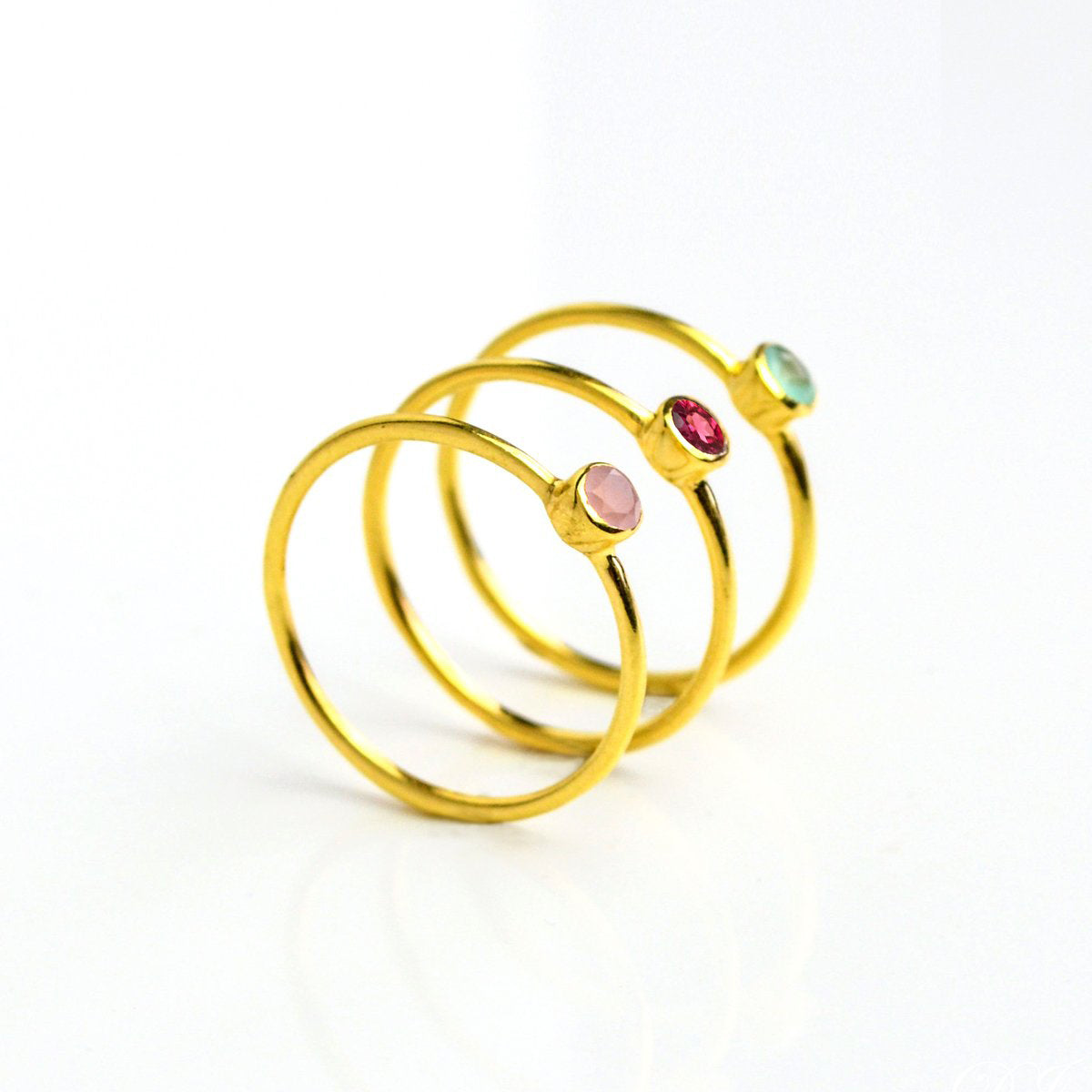 three gold plated dainty 3mm clear quartz gemstone rings featuring aqua chalcedony, garnet, and pink chalcedony. On white background. 925 sterling silver, birthstone ring, stacking ring, stackable, birthstone jewelry, facet gemstone