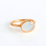 Rose gold solitaire moonstone ring with an oval faceted gemstone showing shimmering adularescence; thin minimalist band, stacking-friendly and handmade—perfect June birthstone jewelry and an elegant anniversary or promise gift for her.