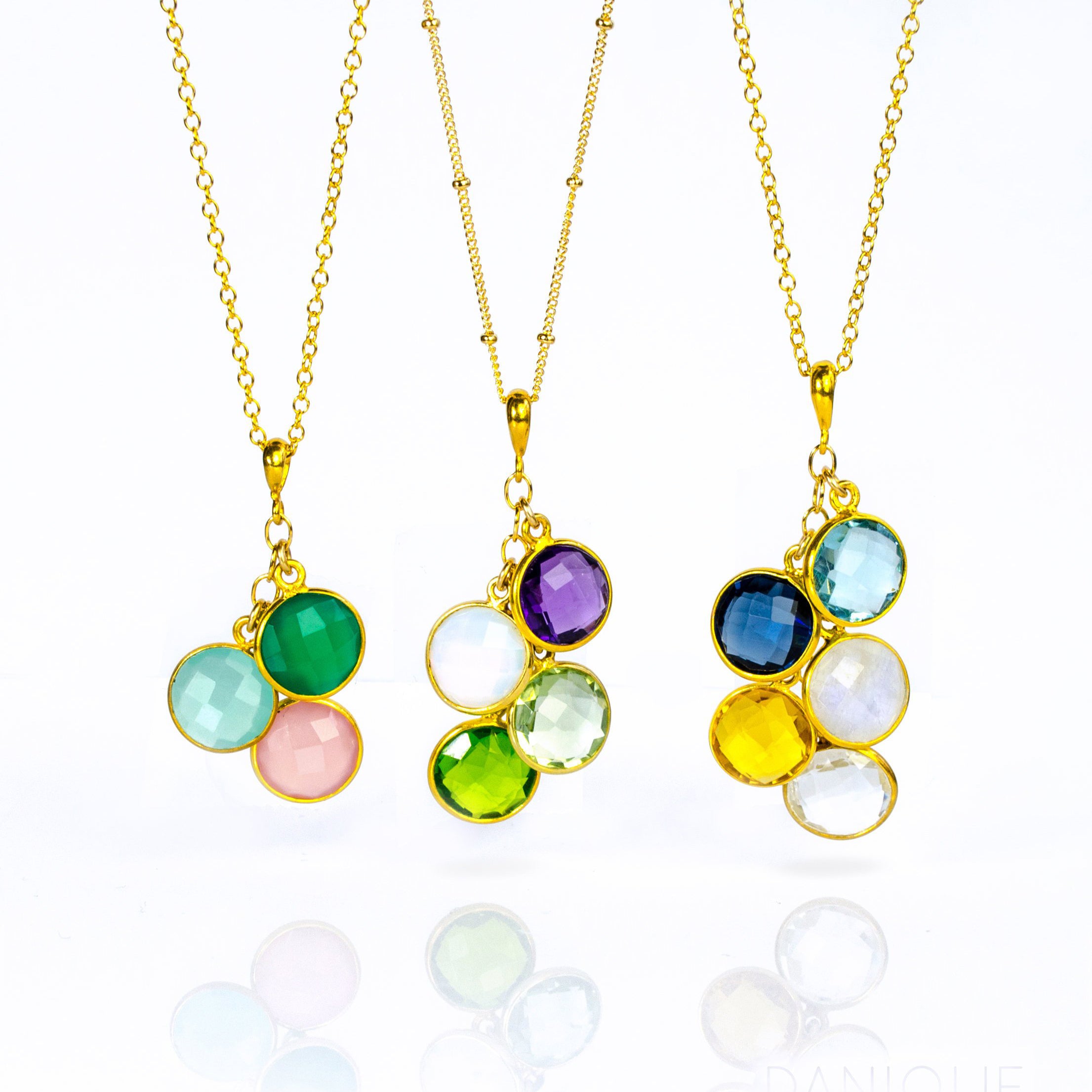 Three gold round cascade necklaces. First cable style necklace with green onyx, aqua chalcedony, and pink chalcedony. The middle necklace features the satellite chain with purple amethyst, moonstone, green amethyst and peridot birthstones. The last cable chain necklace has sky blue topaz, kyanite, moonstone, citrine and clear birthstones. 