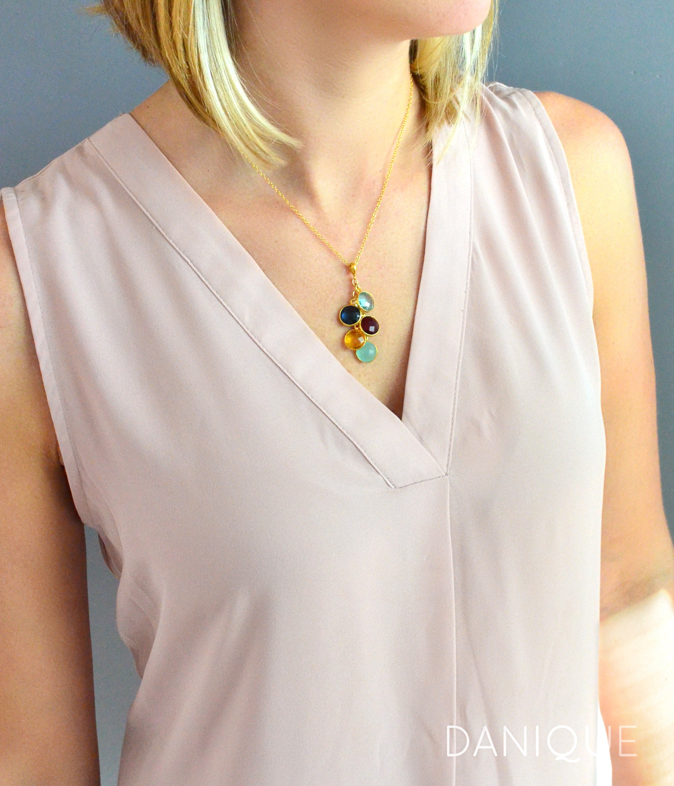 Model is wearing gold cascade cable chain necklace with sky blue quartz, kyanite, black onyx, citrine and aqua chalcedony birthstones.