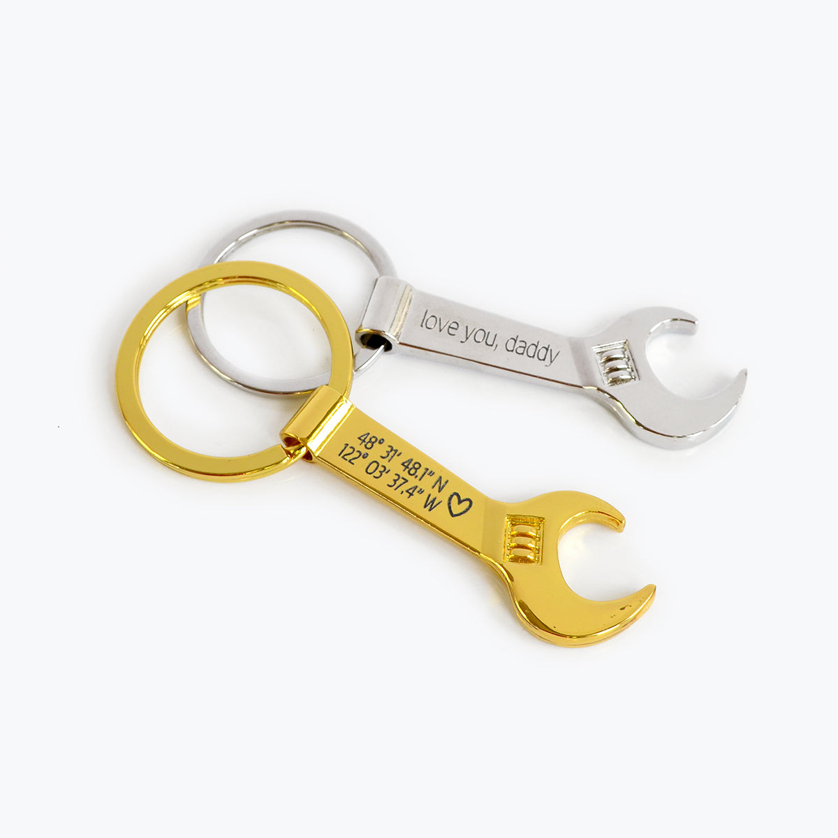 Single gold toned wrench keychain with special GPS coordinates engraved and a heart emoji. Single silver toned wrench bottle opener keychain with special message engraved.