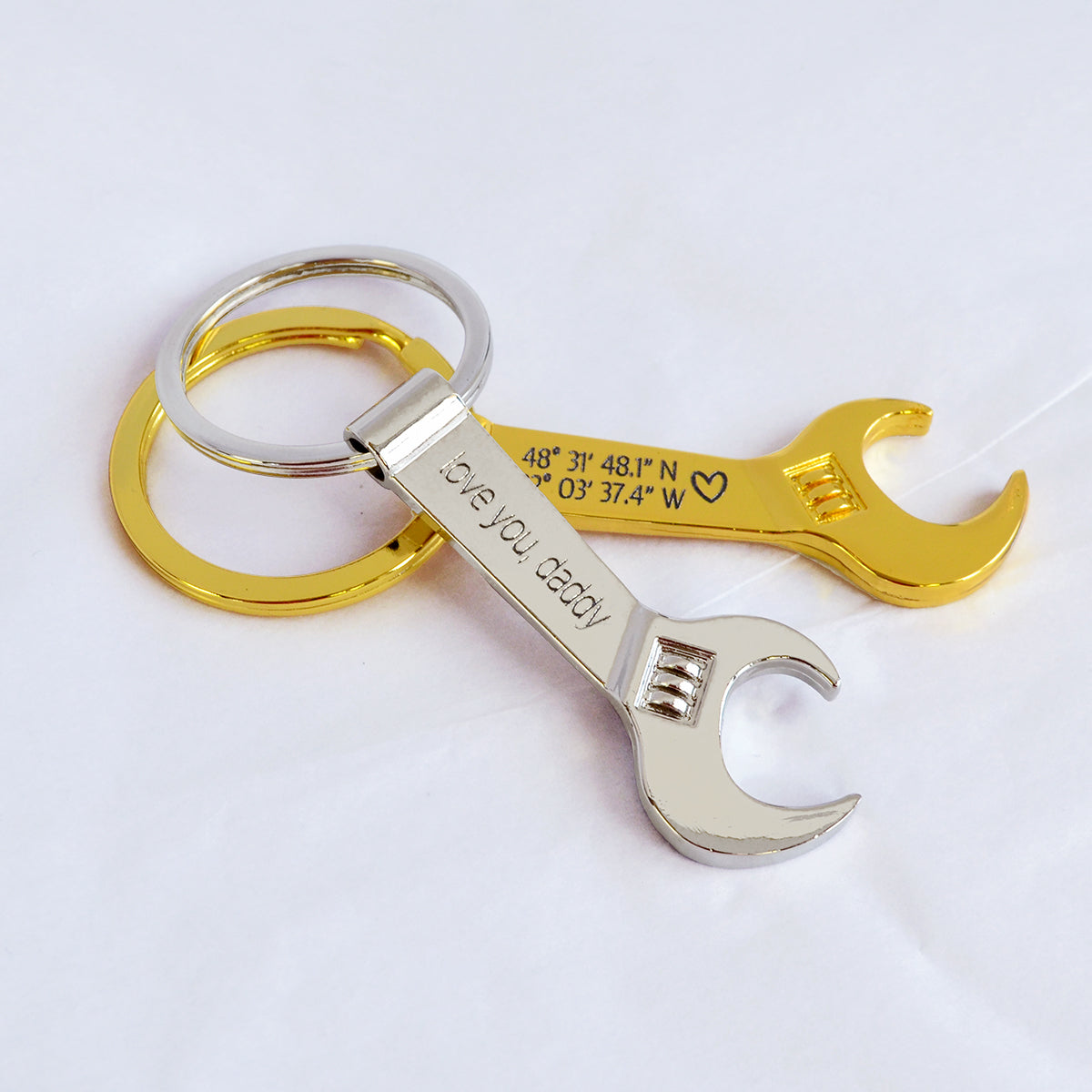 Single gold toned wrench keychain with special GPS coordinates engraved and a heart emoji. Single silver tone wrench keychain engraved with special message. bottle opener keychain