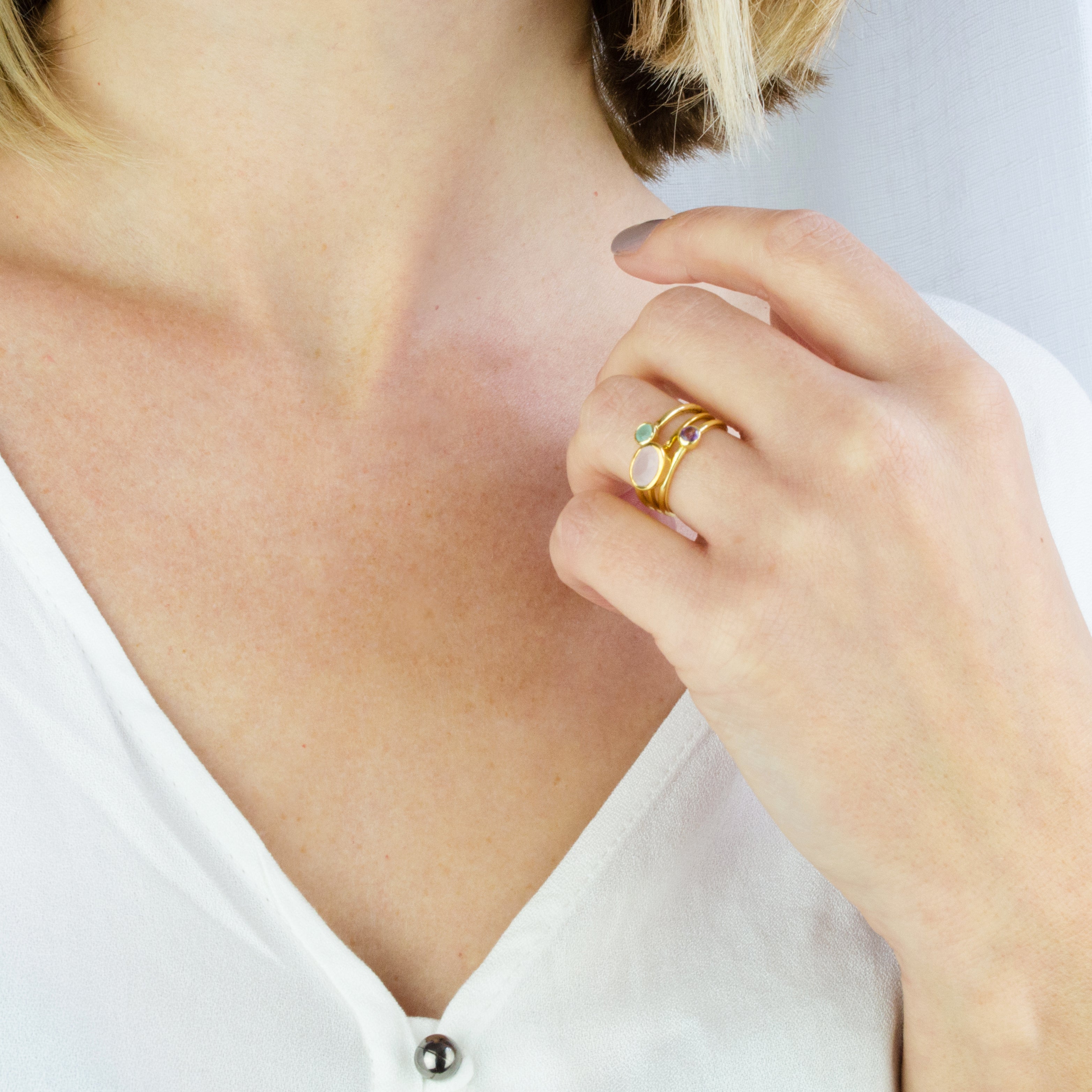 Model wearing a collection of tiny moonstone, tiny rounds purple amethyst and aqua chalcedony in gold filled. 