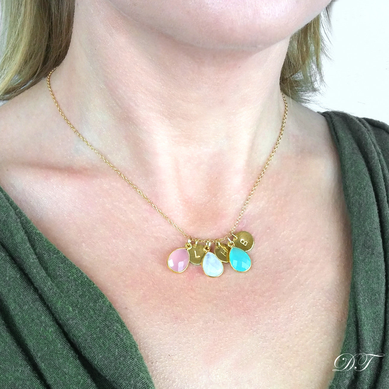 Model in green top is wearing a gold filled teardrop birthstone and hand stamped initial disc necklace with pink chalcedony, moonstone and aqua chalcedony birthstones. 