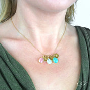 Model in green top is wearing a gold filled teardrop birthstone and hand stamped initial disc necklace with pink chalcedony, moonstone and aqua chalcedony birthstones. 