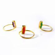Colorful Adira baguette gemstone rings shown in gold settings.