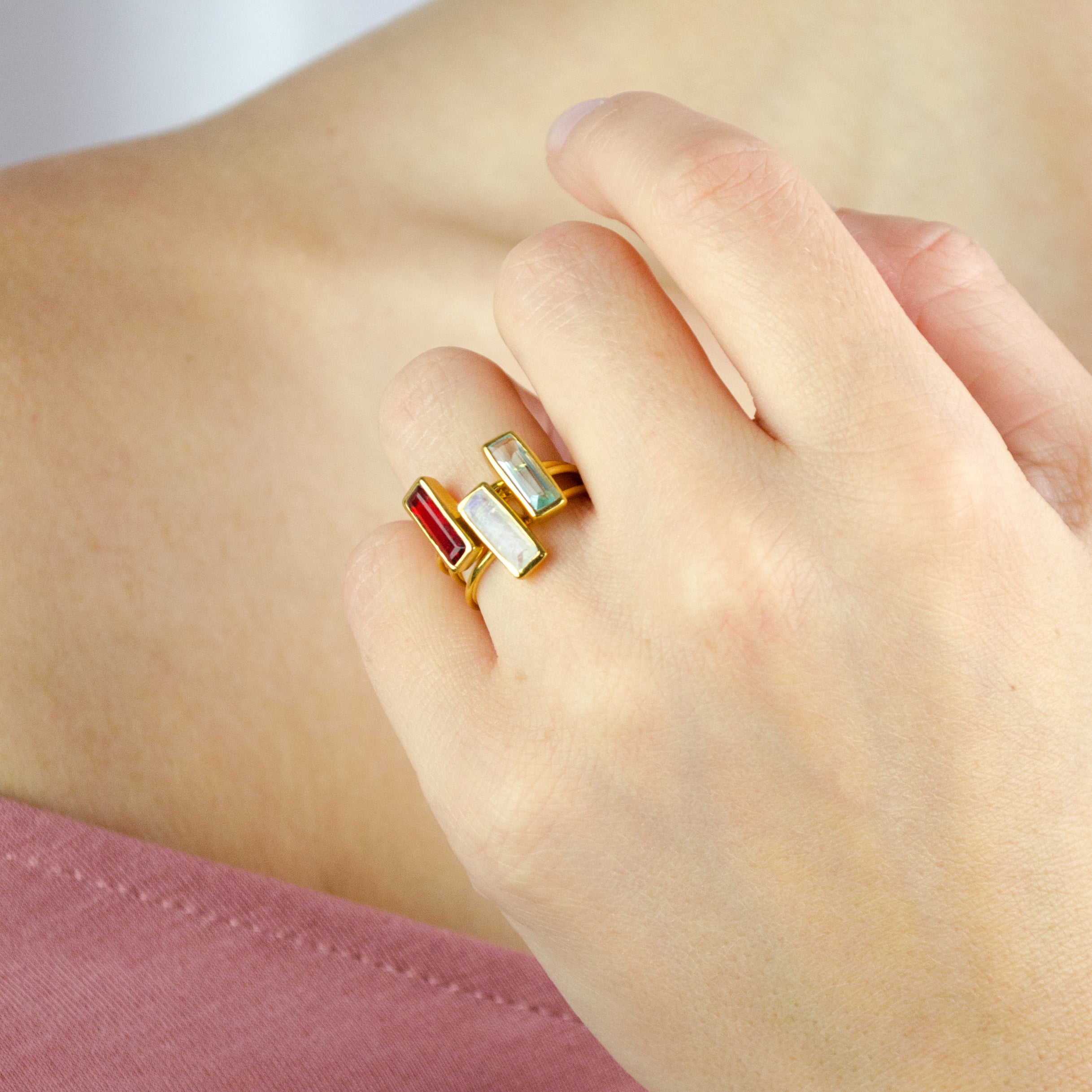 Tiny rectangular gemstone bar rings in multiple birthstone colors worn together as a stacking ring set.
