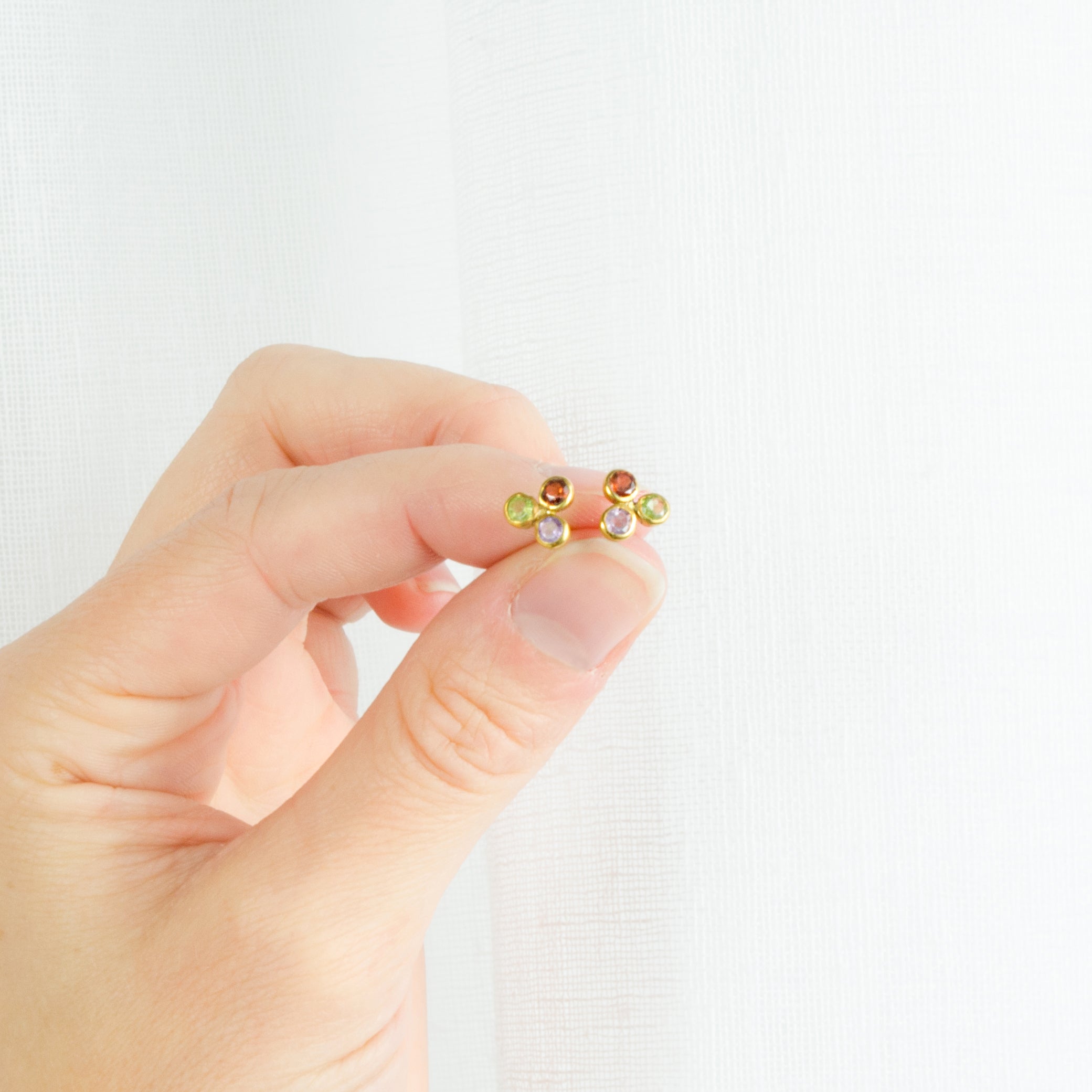 Model is holding our 3mm cluster stud earrings with peridot, garnet and purple amethyst birthstones. 