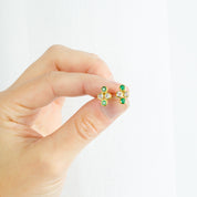 Model holding the gold filled 4 cluster birthstone earrings with two clear and two green onyx stones. 
