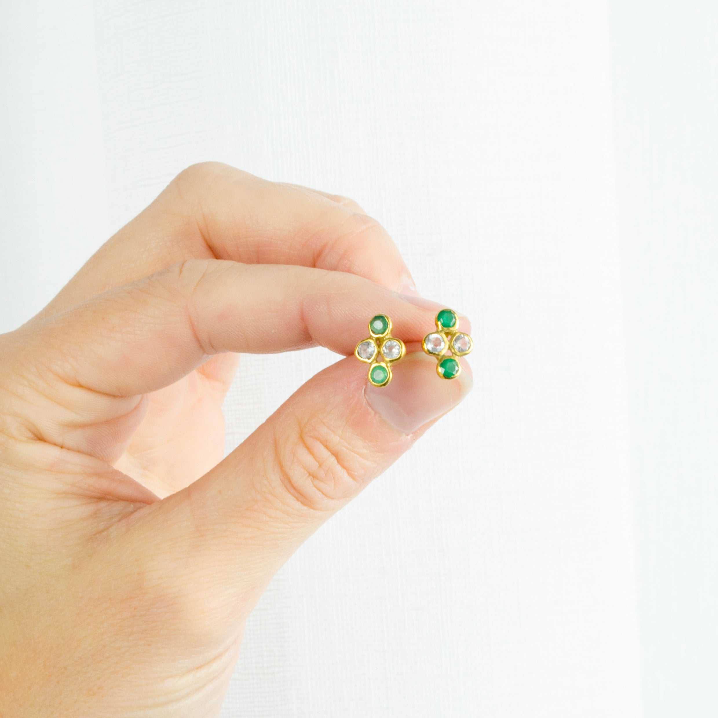 Model holding the gold filled 4 cluster birthstone earrings with two clear and two green onyx stones. 