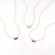 Three tiny gold filled adira bar necklaces on white background featuring garnet, moonstone and purple amethyst birthstones. 