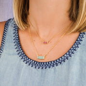 Model in blue top is stylishly layering our horizontal aqua chalcedony adira bar and tiny adira bar necklace with ruby birthstone - perfect layering necklace