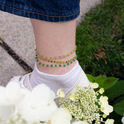 Model is fashionably sporting three anklets from our collection including gold filled wire wrapped peridot and green onyx gemstones as well as a gold filled chain anklet. 