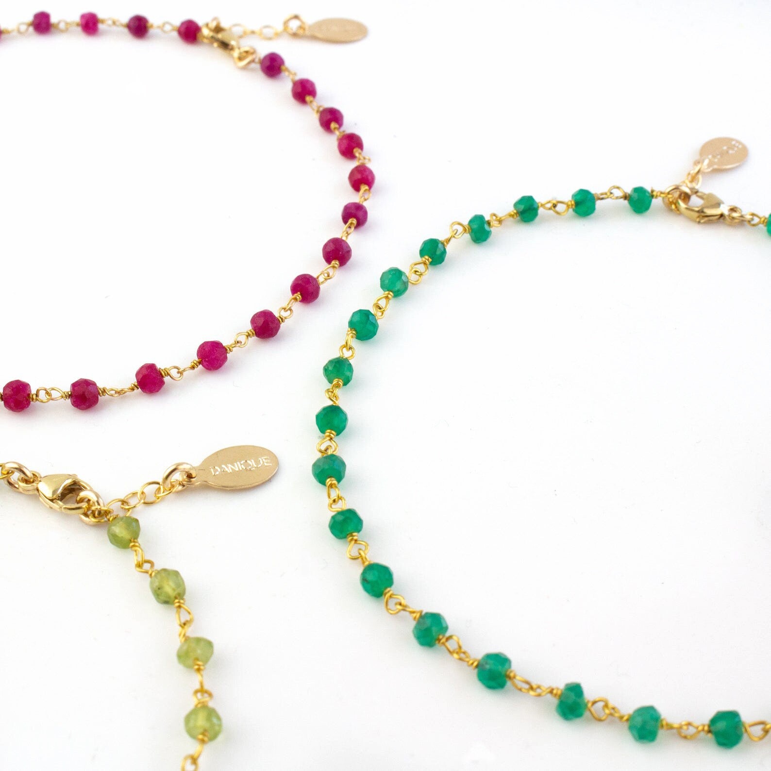Detailed view of the gold filled anklet trio with ruby, green onyx and peridot gemstones. 