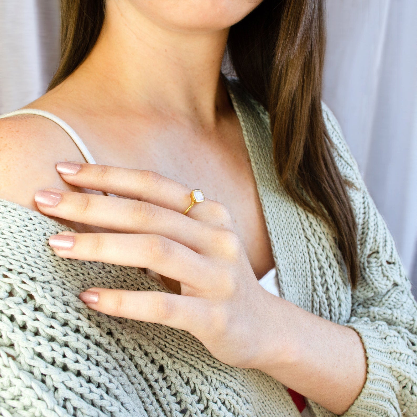 Model in sweater is wearing a single gold plated pink chalcedony birthstone ring. birthstone jewelry pink ring october birthstone